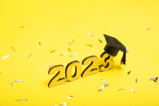 2023년 개념의 클래스 노란색 배경에 검은색 졸업 모자가 있는 2023년