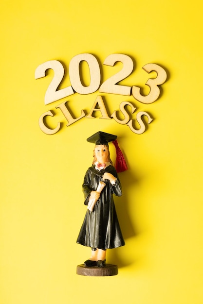 Class of 2023 concept Wooden number 2023 with graduate statuette on color background