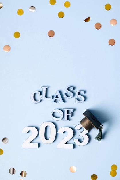 Class of 2023 concept Wooden number 2023 with graduated cap on blue background with tinsel top view