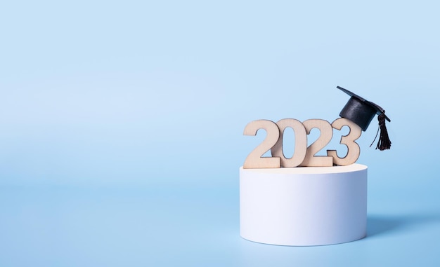 Class of 2023 concept Wooden number 2023 with graduated cap on podium on colored background