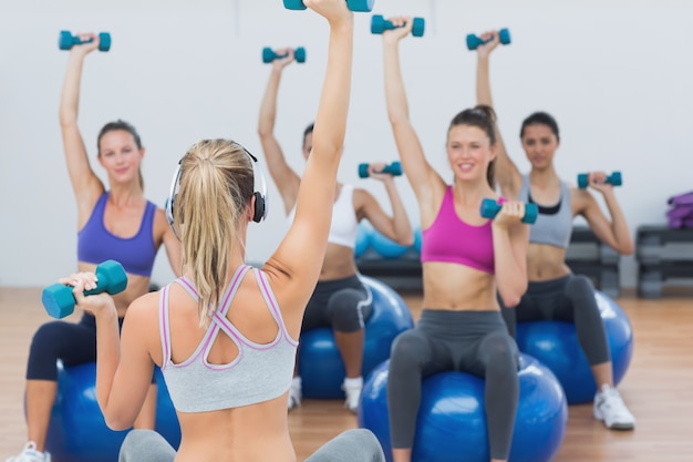 Class exercising with dumbbells on fitness balls