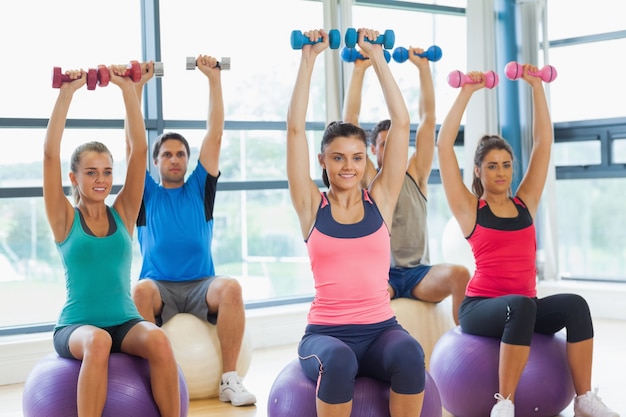 Class exercising with dumbbells on fitness balls