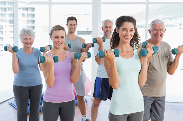 Class exercising with dumbbells in gym