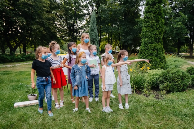 Una classe di scolari mascherati è impegnata in allenamenti all'aperto durante l'epidemia. ritorno a scuola, apprendimento durante la pandemia.