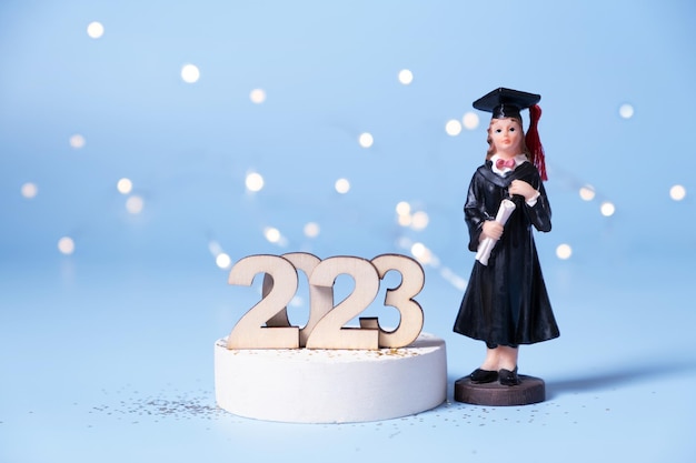 Фото Концепция класса 2023 года деревянный номер 2023 со статуэткой выпускника на цветном фоне с боке
