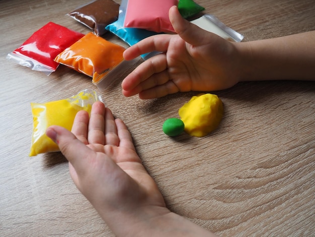 Classes with plasticine childrens hands crumple soft plasticine\
packages with plasticine are on the table creativity for the\
development of fine motor skills of hands creating from\
plasticine