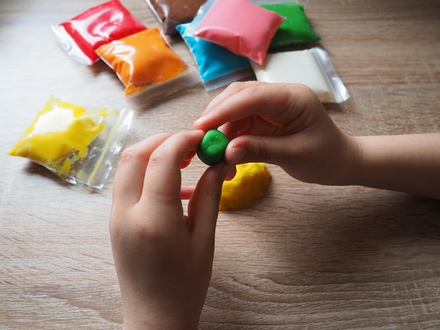 Classes with plasticine childrens hands crumple soft plasticine\
packages with plasticine are on the table creativity for the\
development of fine motor skills of hands creating from\
plasticine