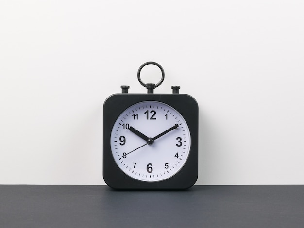 Classic alarm clock with hands on a black and gray background. Crassic dial.