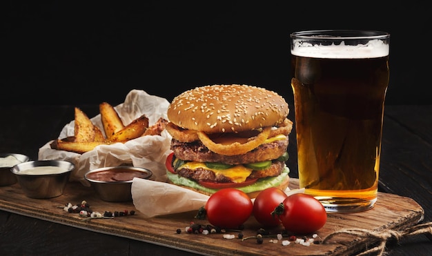 Classic american burger with hot grilled patty, melted cheese, tomatoes, onion, sauces, fried chips and beer