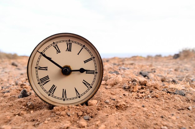 Foto orologio analogico classico nella sabbia sul deserto della roccia