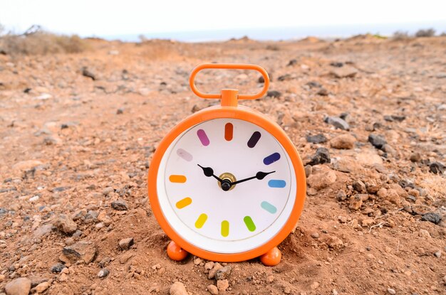 Foto orologio analogico classico nella sabbia sul deserto della roccia