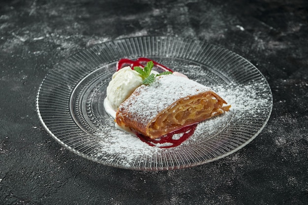 Classic Austrian pastry - puff pastry strudel with apple, nuts and ice cream on a dark table. Close up, selective focus