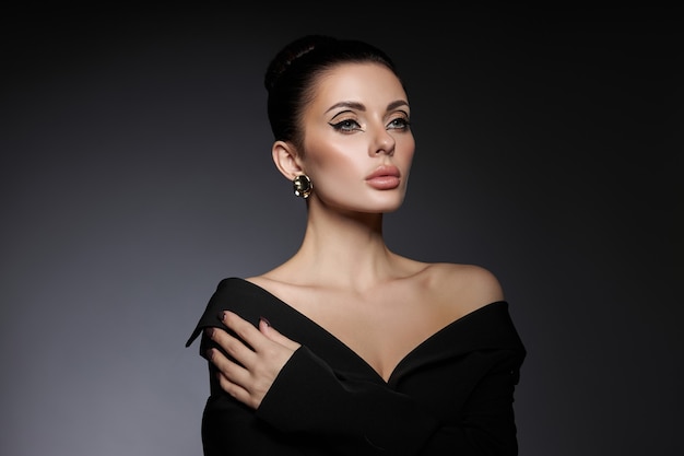 Classic beauty portrait of woman with perfect evening makeup on dark background. Perfect skin without wrinkles, professional beauty makeup, long eyelashes. Perfect girl in black clothes