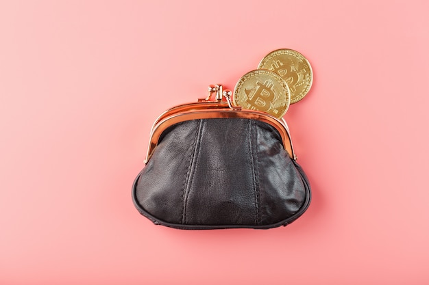 Classic black wallet with bitcoin coins on a pink wall.