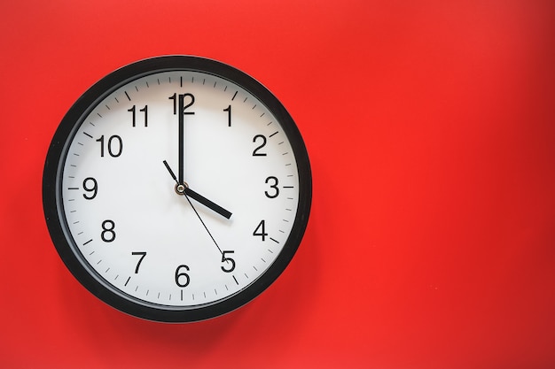 Classic black and white analog clock on red background at Four o'clock with copy space