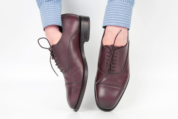 Classic brown shoes worn on the hands on a white background. Leather Fashionable shoes for men