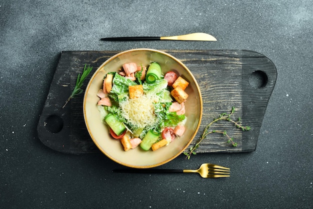 Classic Caesar salad with salmon On a black stone background In a plate closeup