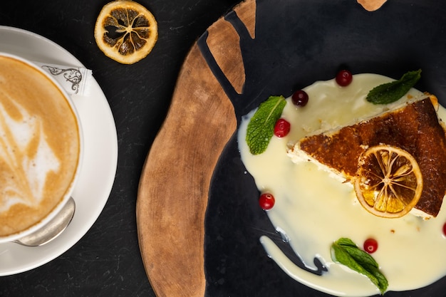 Classic cheesecake on a black background dessert on a black\
background in a black plate latte coffee in a white cup