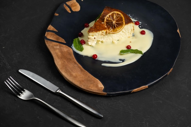 Classic cheesecake on a black background dessert on a black\
background in a black plate