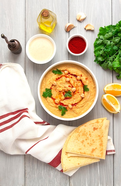 Classico hummus di ceci con olio d'oliva tahini, aglio e paprika fatto in casa su fondo bianco