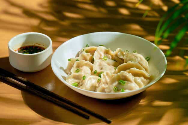 Classic Chinese boiled dumplings with meat and spicy soy sauce in a white plate. Chinese cuisine