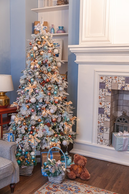 Stanza interna decorata classica di natale, albero del nuovo anno con le decorazioni d'argento. moderno appartamento di design d'interni in stile classico blu con camino e albero di natale. la vigilia di natale in casa.