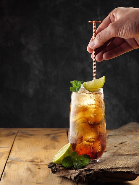 Classic cocktail Cuba Libre on a wooden table, copy space.