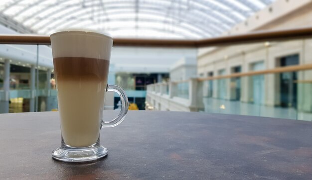 Caffè classico latte macchiato in una tazza di vetro sul tavolo. tazza di vetro con bevanda calda.