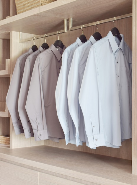 Classic color shirts hanging in warm wooden wardrobe