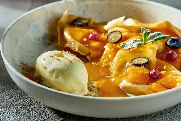 Classic crepe suzette with orange jam ice cream and berries in a plate A delicious dessert