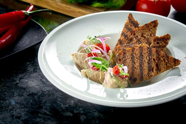 Piatto classico della cucina israeliana - forshmak di aringhe con crostini di pane servito in un piatto bianco su un tavolo di marmo. frutti di mare.