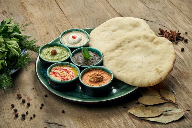 Classic eastern snacks with pita - meze. Set in small bowl - Hummus, hot pepper paste often with walnuts, yogurt, eggplant paste.