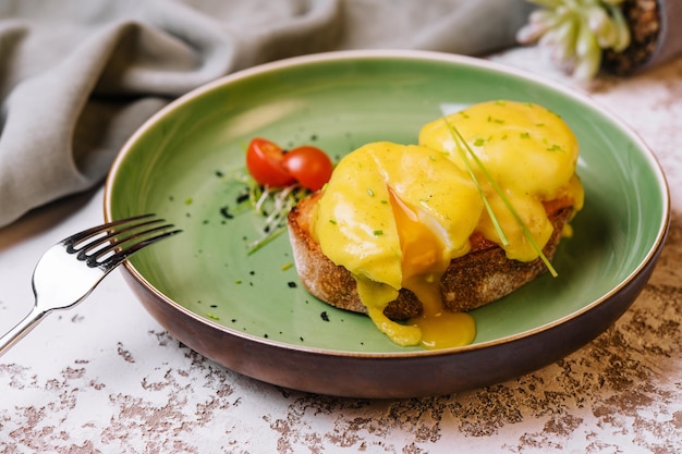 Classic egg benedict on green plate