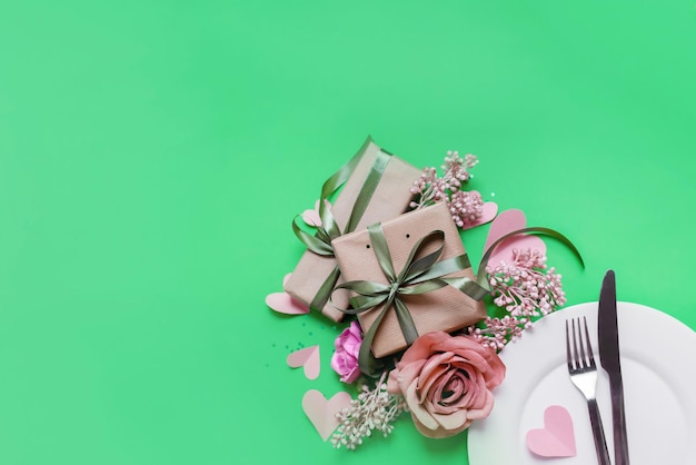 Classic festive table setting in valentine's day style with gifts and hearts on a green background.