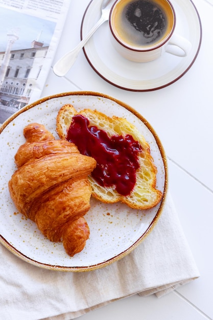 잼 커피와 신문이 포함된 크루아상이 포함된 고전적인 프랑스식 아침 식사