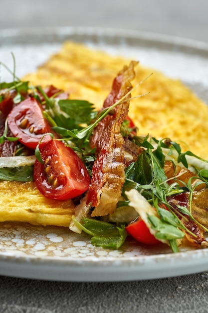 Classic French omelette with crispy bacon and vegetable salad with tomatoes in plate Food photo for menu