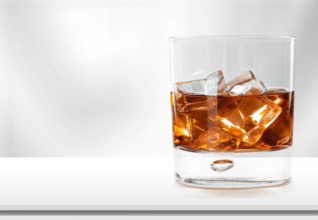 A classic glass of whiskey with ice cubes on the desk