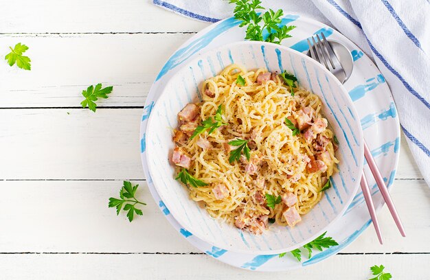 Classic homemade carbonara pasta with pancetta, egg, hard parmesan cheese and cream sauce. Italian cuisine. Spaghetti alla carbonara. Top view, copy space