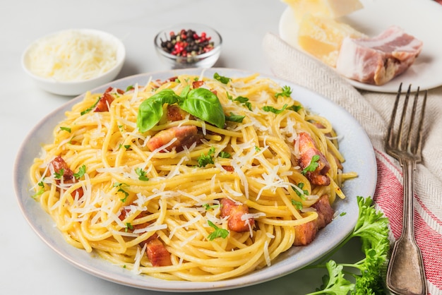 Classic homemade italian pasta carbonara with bacon, eggs, parmesan cheese and parsley in a plate with fork