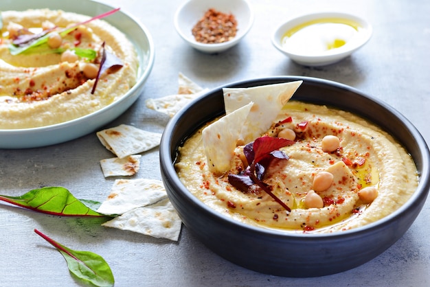 Classic hummus in a bowl with herbs, smoked paprika, olive oil and lettuce