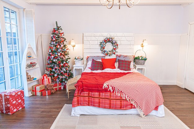 Classic interior room with Christmas tree and traditional white red decorations. Modern clean white classical style interior design apartment bedroom. Christmas eve at home. Minimalist home design.