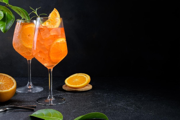 Классический итальянский аперитив aperol spritz коктейль в двух стаканах с кусочком льда апельсина на черном фоне
