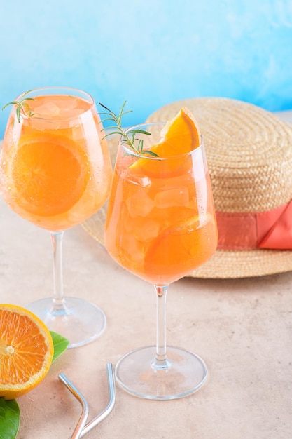 Классический итальянский аперитив aperol spritz коктейль в двух стаканах с ледяным апельсином на синем фоне