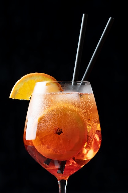 Классический итальянский коктейль Aperol Spritz в стакан на черном, крупным планом