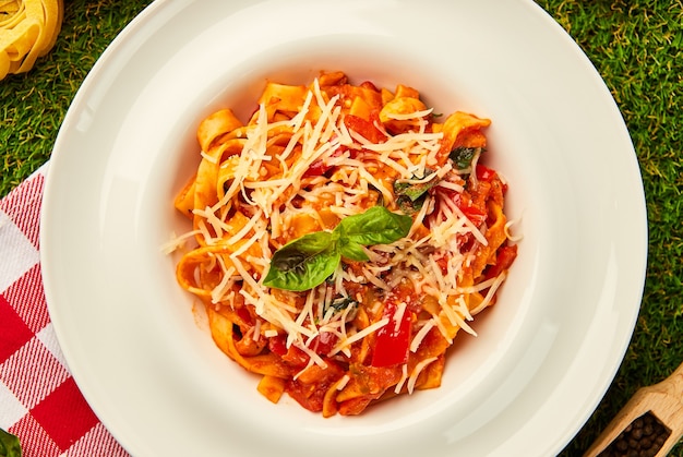 Classic italian pasta arrabbiata with basil and freshly parmesan cheese on a green grass