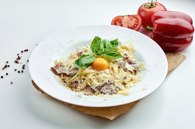 Classic Italian pasta (spaghetti) carbonara with bacon, yolk, parmesan cheese in a white plate on a white plate