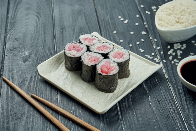 Classic japanese sushi rolls - maki rolls with tuna on a white, ceramic plate on a black wooden background