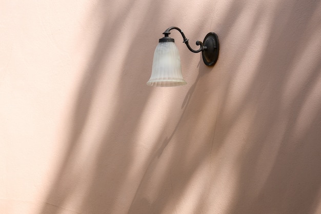 Classic lamp on pink cement wall with shadow from tree branch