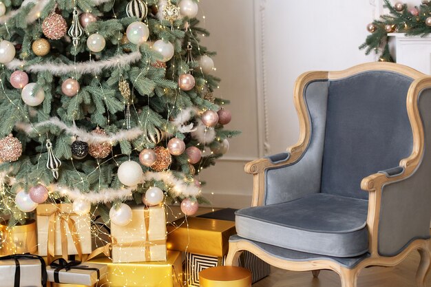 Classic living room interior with blue armchair and decorated chic Christmas tree gifts