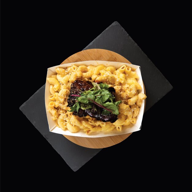 Classic Mac and Cheese served in a dish isolated on wooden board side view on black background fast food